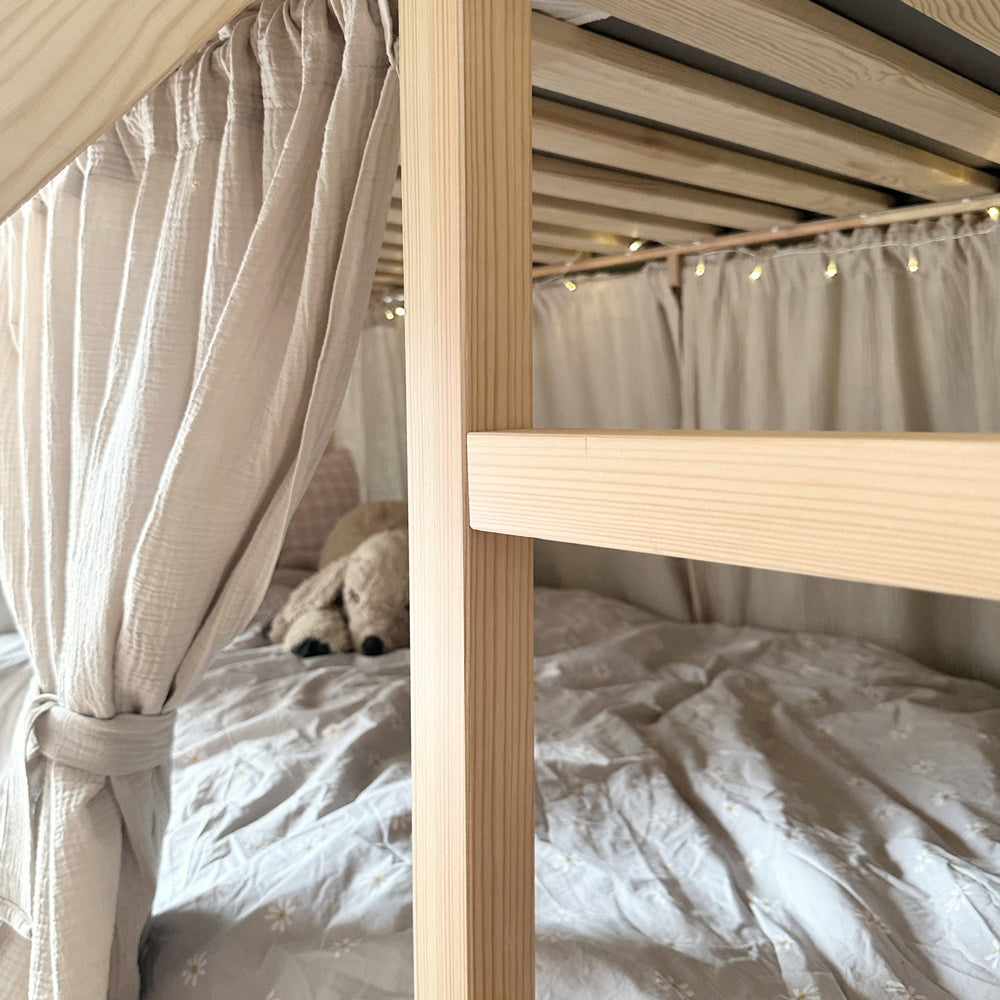 Nahaufnahme des Kura Bettes mit Vorhangstange und passenden Vorhängen aus Musselin.