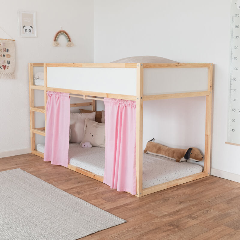 Ikea Hochbett mit einem rosa farbenden Vorhang an der Leiterseite