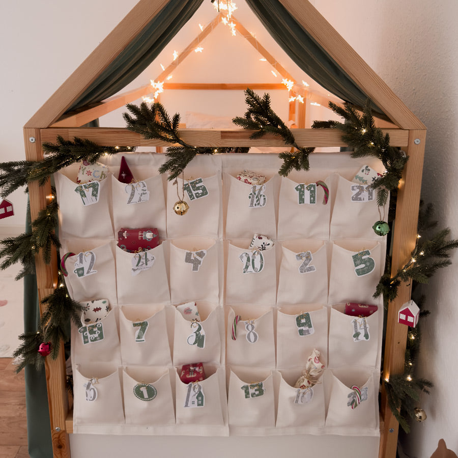 Selbst gestalteter Adventskalender mit 24 Taschen, der an der Stirnseite des IKEA Kura Bettes hängt.