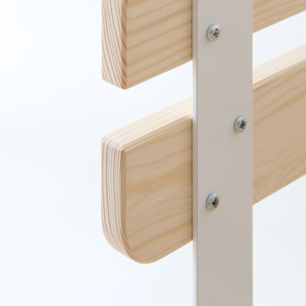 Detailaufnahme der seitlichen Befestigung des Rausfallschutzes für das IKEA KURA Kinderbett: abgerundete Holzenden aus hellem Kiefernholz sind mit einer weißen Metallleiste und Schrauben stabil verbunden.