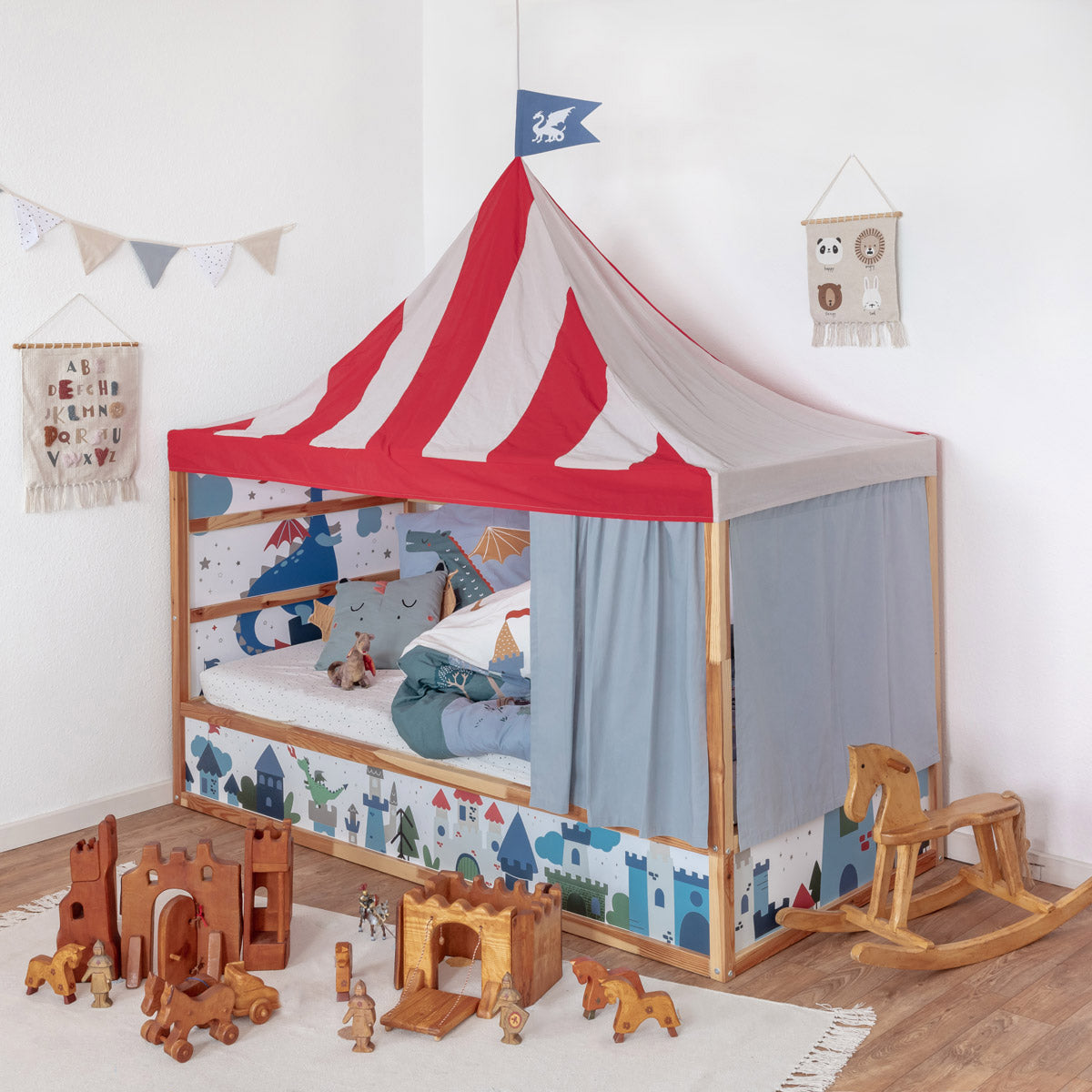 Kinderzimmer mit Ikea Kura Kinderbett mit Ritter Betthimmelset in Rotweiss mit Flagge, blauen Bettvorhängen und Ritter Stickerset