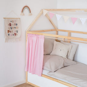 Teilansicht eines Ikea Kinderbetts mit bunter Wimpelkette und einem rosa Vorhang